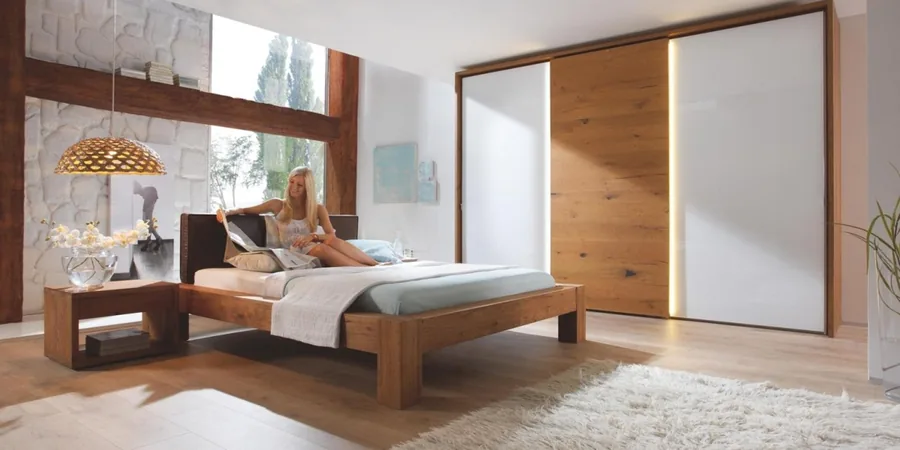 Schlafzimmer mit massivem Eichenbett, Schiebetürenschrank und Fensterfront.