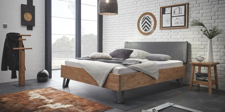 Schlafzimmer mit Bett im Used-Look, Kleiderständer und weißer Ziegelwand.