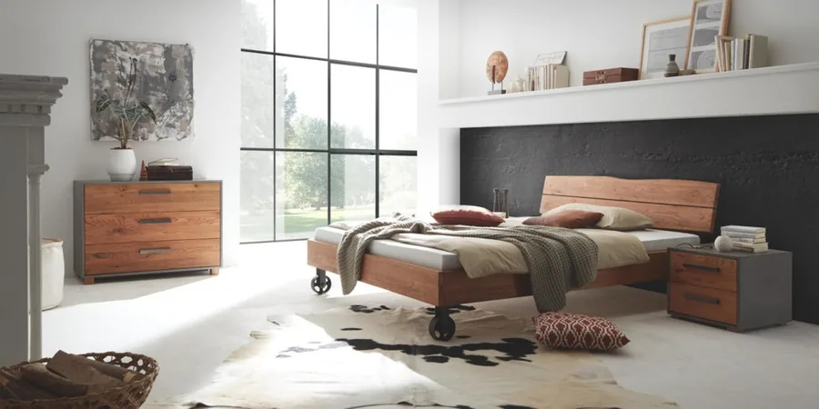 Schlafzimmer mit Wildeichenbett, Nachttisch, Kommode und schwarzer Akzentwand.