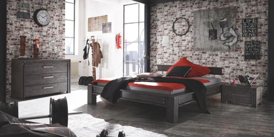 Schlafzimmer im Industrie-Stil mit dunklem Holzbett, roten Kissen und Backsteinwand.